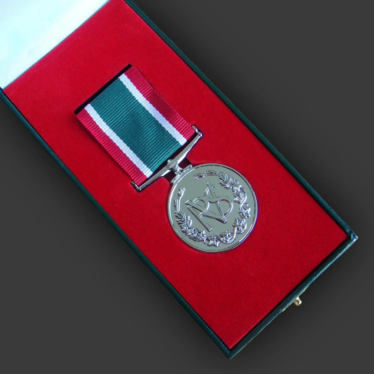 Volunteer service medal in a green presentation case with red lining, made by Selcraft